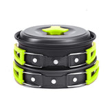 Stack of black and green cookware with a lid on a white background