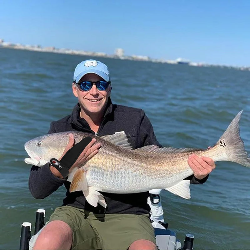 Man holding a large fish by the water with clear skies