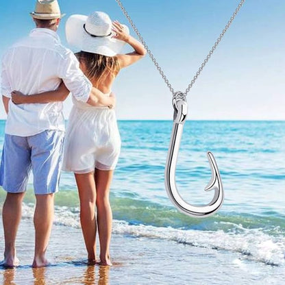 Couple on a beach with a silver fish hook pendant in the foreground
