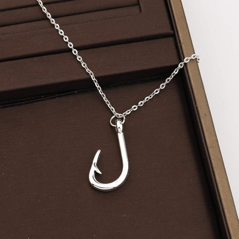 Silver fishing hook necklace on a brown surface