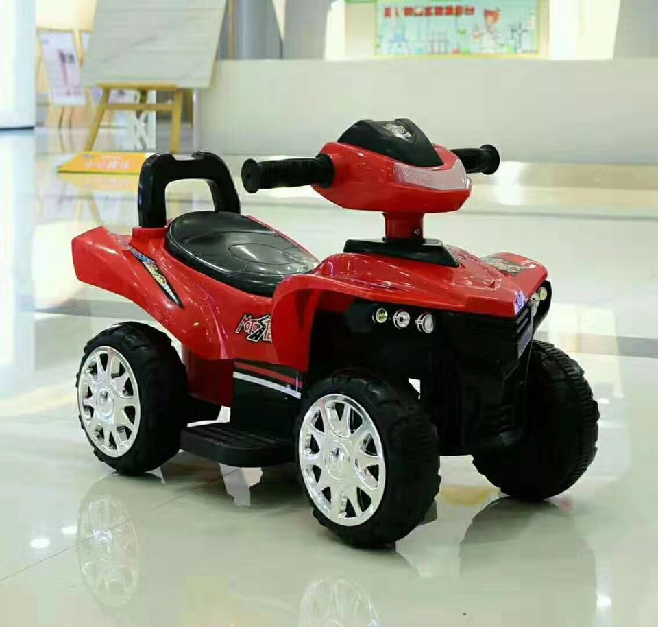 Red toy ATV with black wheels on a reflective floor